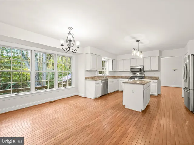 a kitchen with granite countertop a stove top oven a sink dishwasher and wooden cabinets with wooden floor