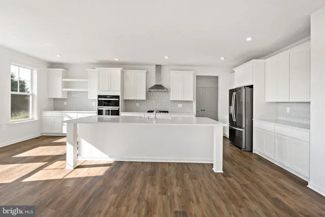 a large white kitchen with wooden floor and stainless steel appliances