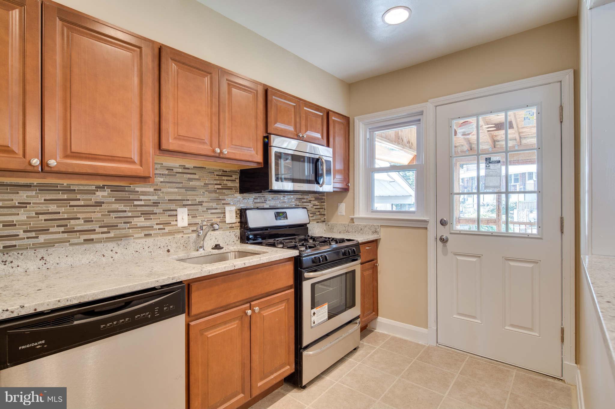 8630 Black Oak Road Baltimore, MD 21234 - Photo 14 of 30 a kitchen with stainless steel appliances granite countertop a stove a sink dishwasher and a microwave oven with white cabinets