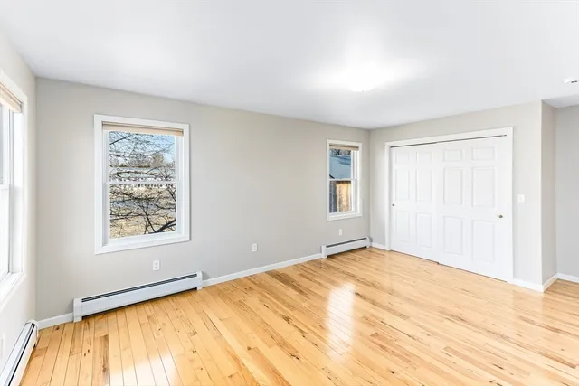 a view of an empty room with window and wooden floor