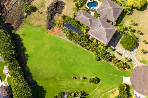 an aerial view of a residential houses with outdoor space and trees all around