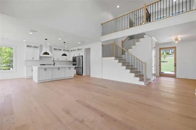 a large white kitchen with kitchen island a large window a sink stainless steel appliances and cabinets