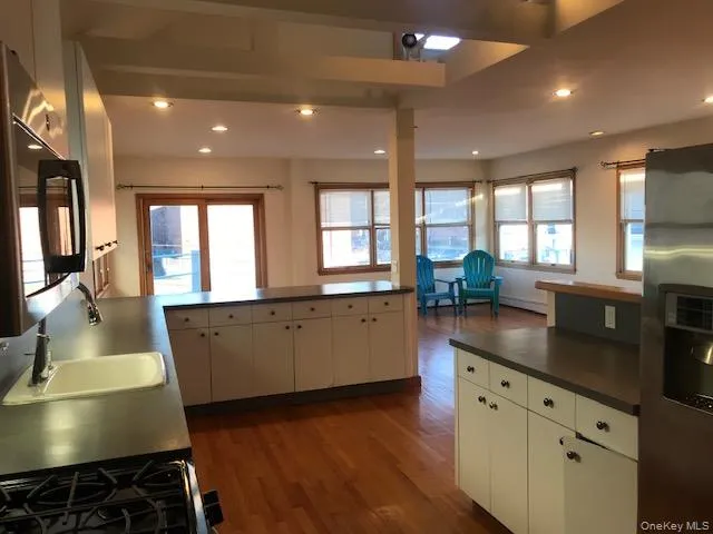 a kitchen with stainless steel appliances granite countertop a sink a stove and a wooden floors