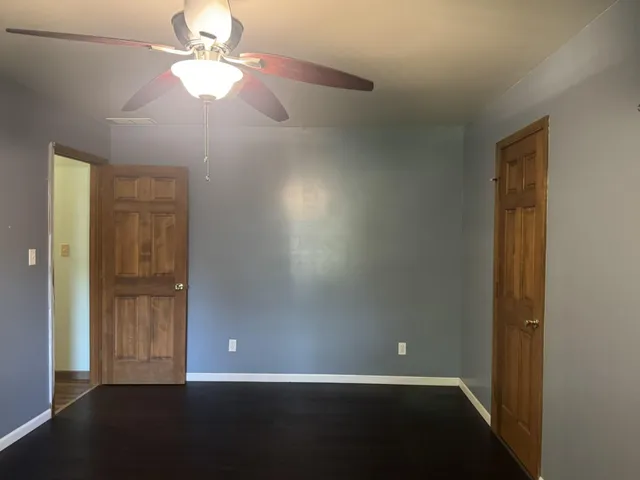 an empty room with wooden floor closet and windows