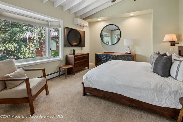 a spacious bedroom with a bed a mirror and a large window with the large mirror