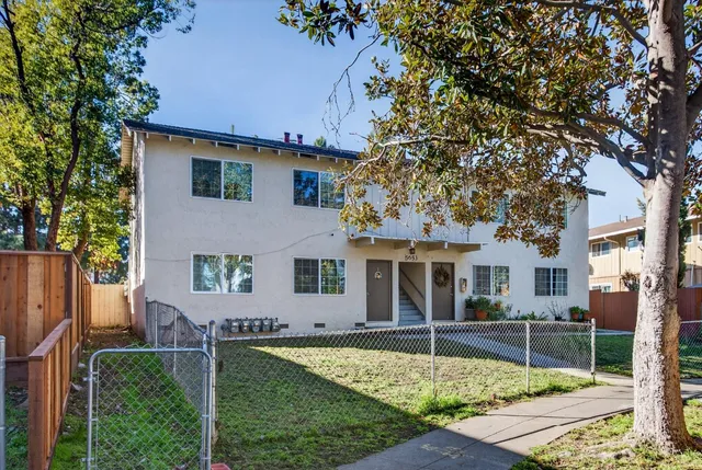 a view of a house with a small yard and wooden fence