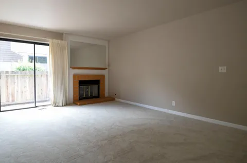 en empty room with windows and fireplace