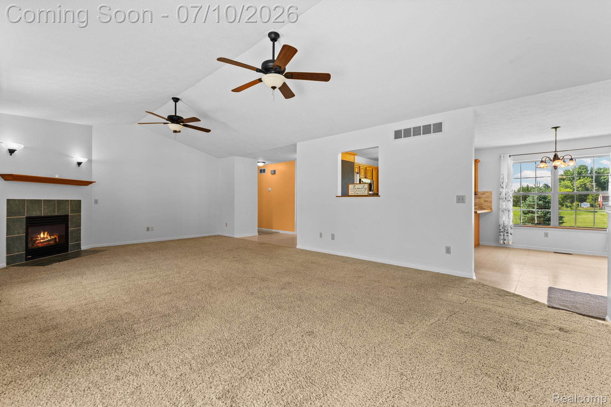 3144 North Nicholson Road Fowlerville, MI 48836 - Photo 35 of 70 Spacious living area featuring vaulted ceilings, a fireplace with a stone surround and wood mantel, and two ceiling fans with integrated lighting