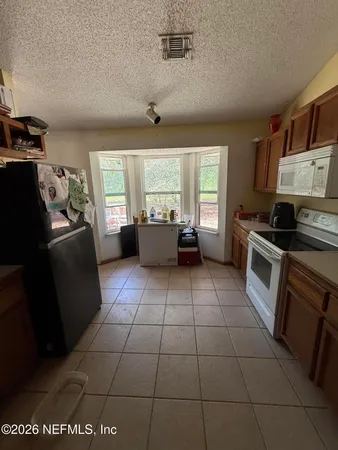 a kitchen with granite countertop a stove a sink a refrigerator and window
