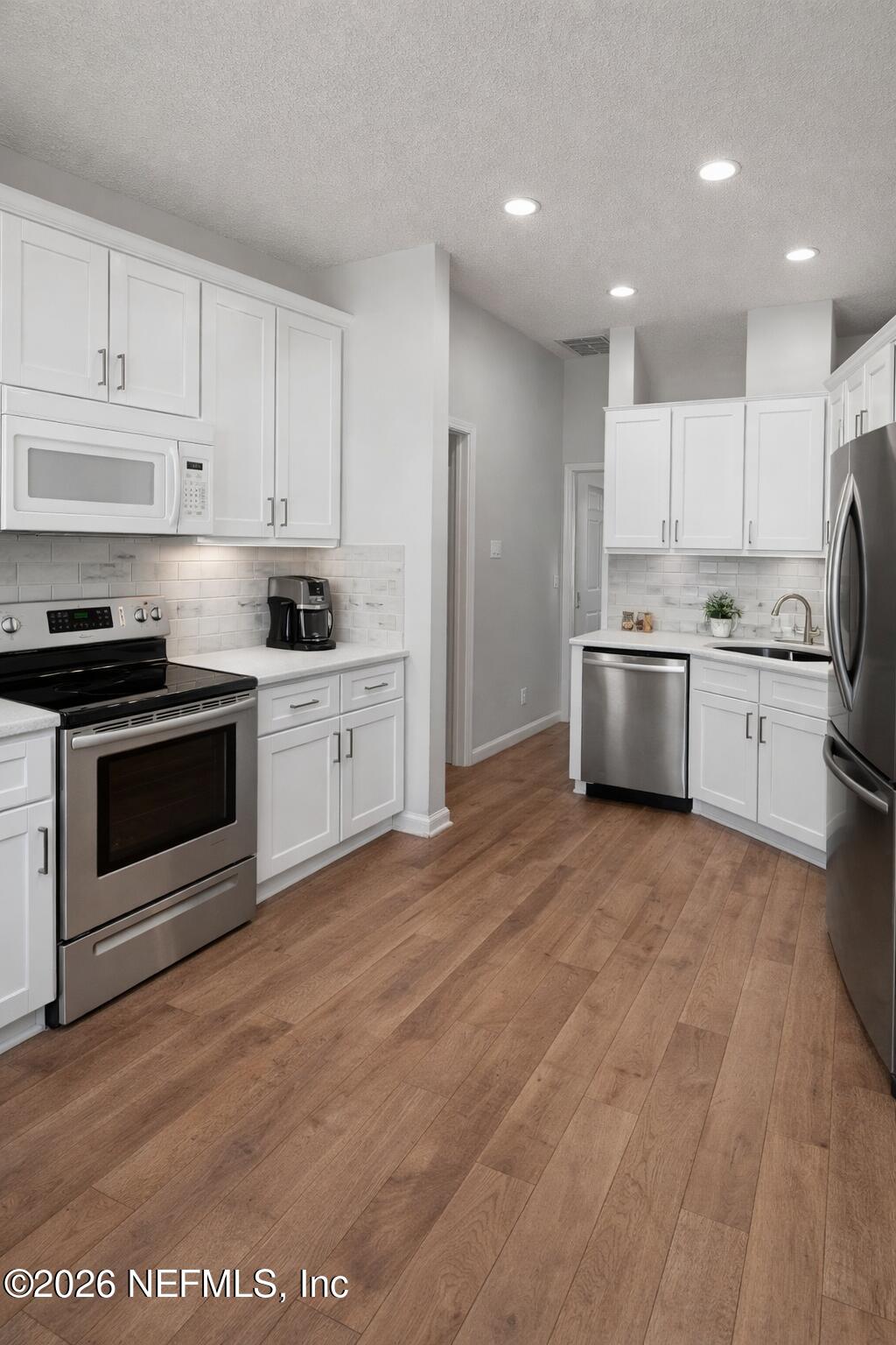 45 Mint Circle Middleburg, FL 32068 - Photo 5 of 24 a kitchen with stainless steel appliances granite countertop a stove top oven a sink and white cabinets