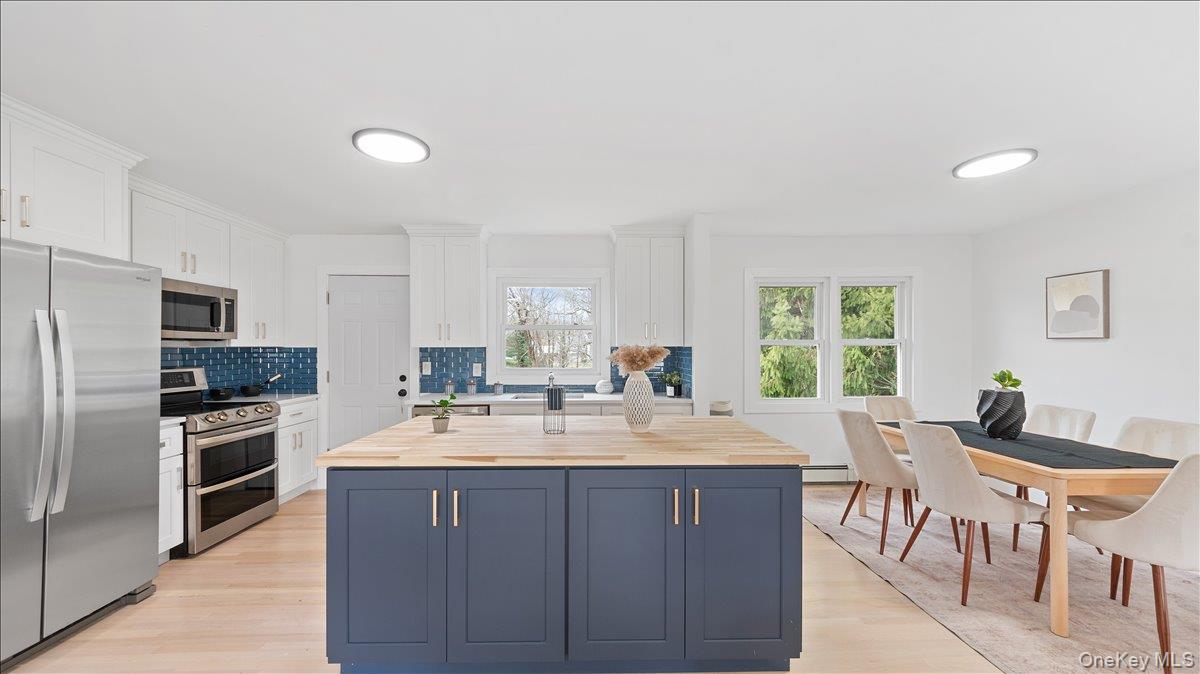 77 Friendly Road Mahopac, NY 10541 - Photo 11 of 36 Kitchen with butcher block counters, stainless steel appliances, two tone color scheme, light wood-style floors, and a center island