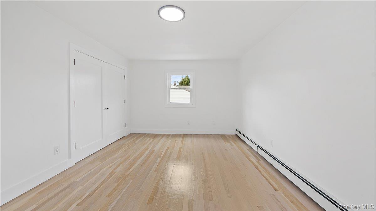 77 Friendly Road Mahopac, NY 10541 - Photo 15 of 36 Unfurnished bedroom featuring a baseboard heating unit, light wood finished floors, and a closet