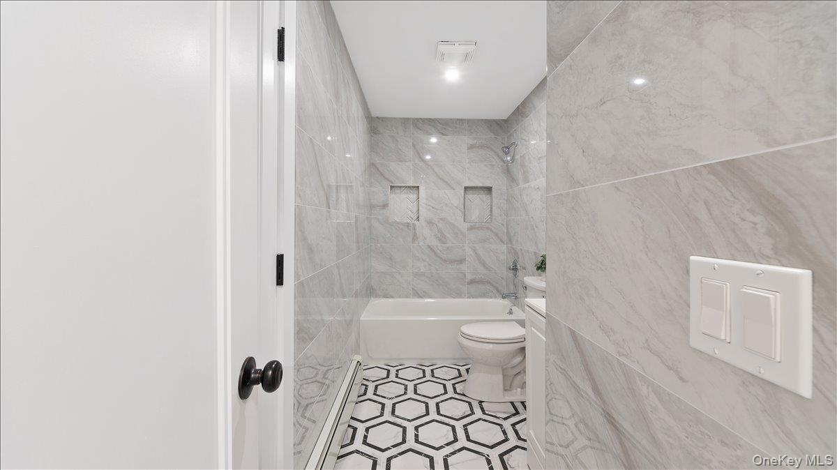 77 Friendly Road Mahopac, NY 10541 - Photo 16 of 36 Main Floor: Full bath with shower combination, tile walls, baseboard heating, tile patterned floors, and vanity