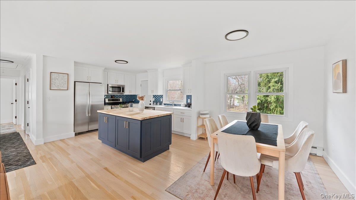 77 Friendly Road Mahopac, NY 10541 - Photo 7 of 36 Two tone kitchen with stainless steel appliances, light countertops, light wood-style floors, two tone color scheme, and a kitchen island