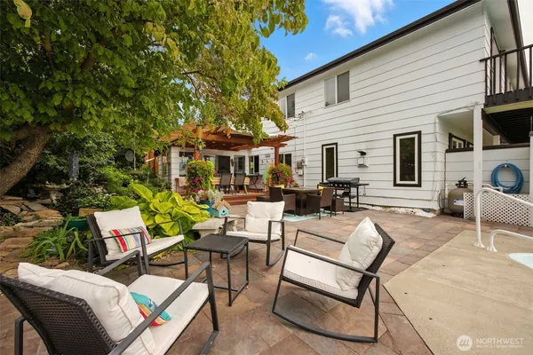 a view of a patio with couches table and chairs with wooden fence and plants