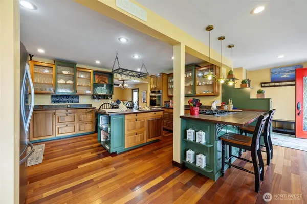 a kitchen with stainless steel appliances kitchen island granite countertop a table chairs and a refrigerator