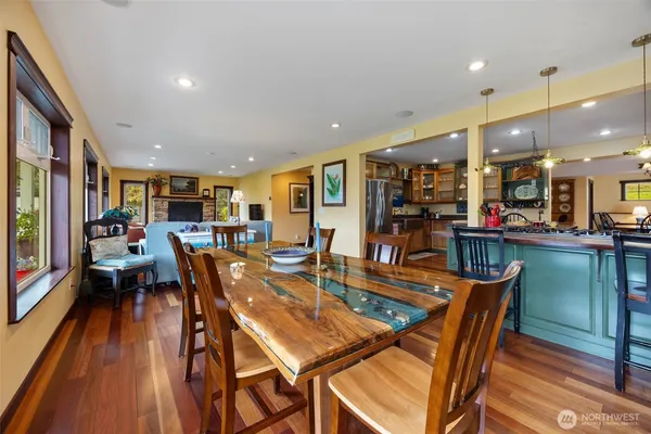 a dining room with stainless steel appliances lots of white furniture wooden floor and a rug