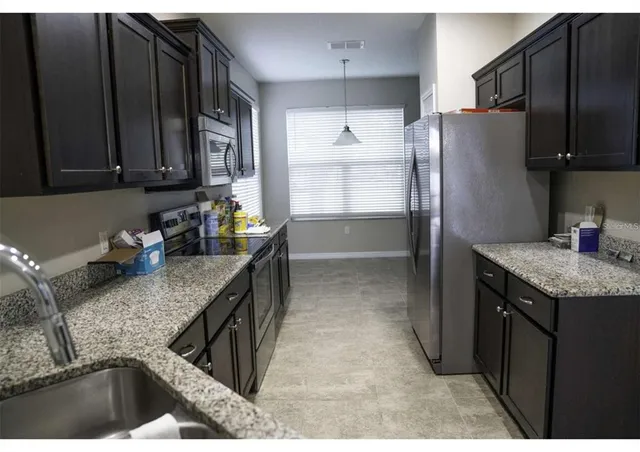 a kitchen with granite countertop a refrigerator a stove and a sink