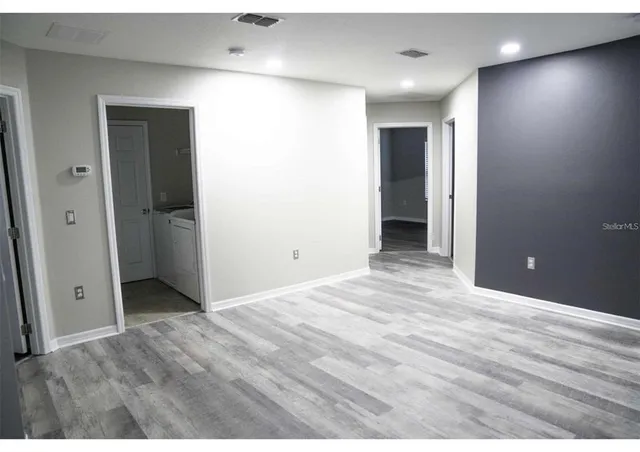 a view of an empty room with closet and wooden floor
