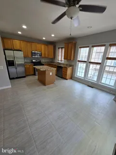 a large kitchen with stainless steel appliances kitchen island granite countertop a large counter top a stove a chimney a sink and a large window