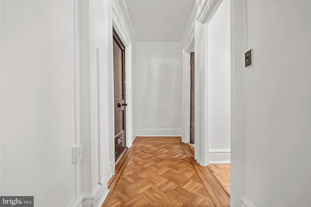 a view of a hallway with wooden floor and a bathroom
