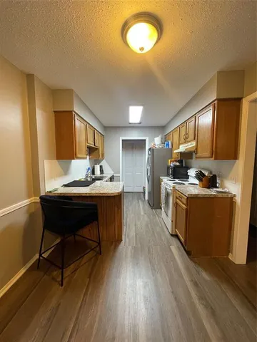 a kitchen with a sink appliances dining table and wooden floor