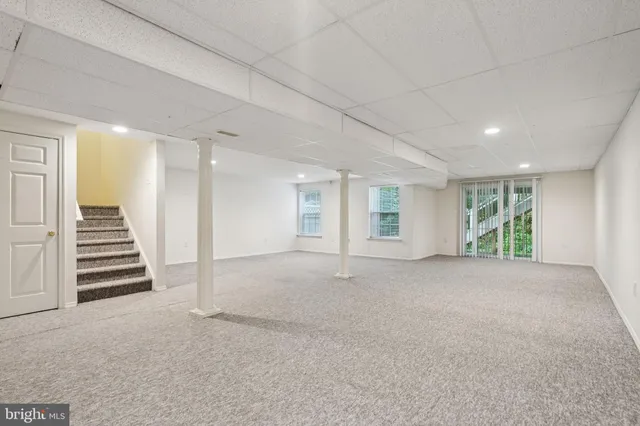 a view of an empty room with wooden floor and stairs