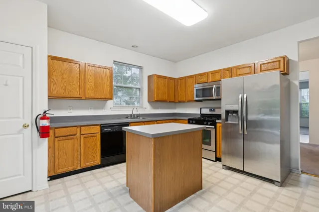 a kitchen with stainless steel appliances granite countertop a refrigerator a stove top oven and sink