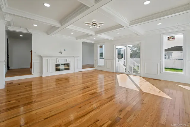 an empty room with wooden floor and a kitchen