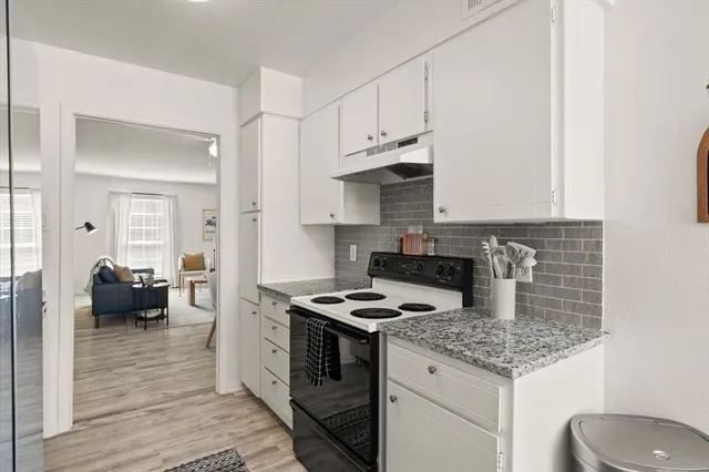 a living room with kitchen island a wooden floor and a chandelier