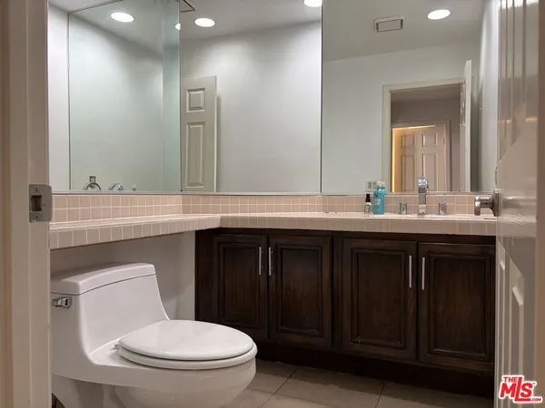 a bathroom with a granite countertop toilet sink and mirror