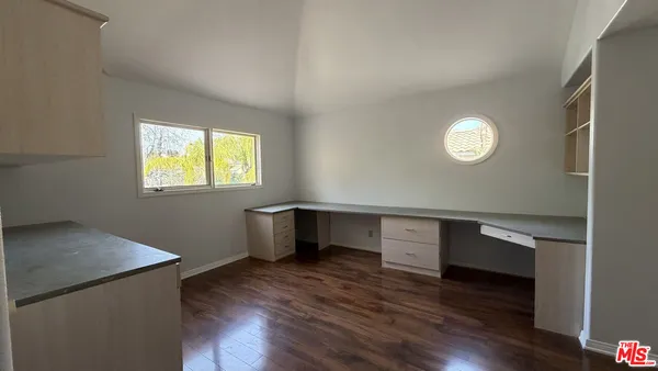 a view of empty room with wooden floor and window