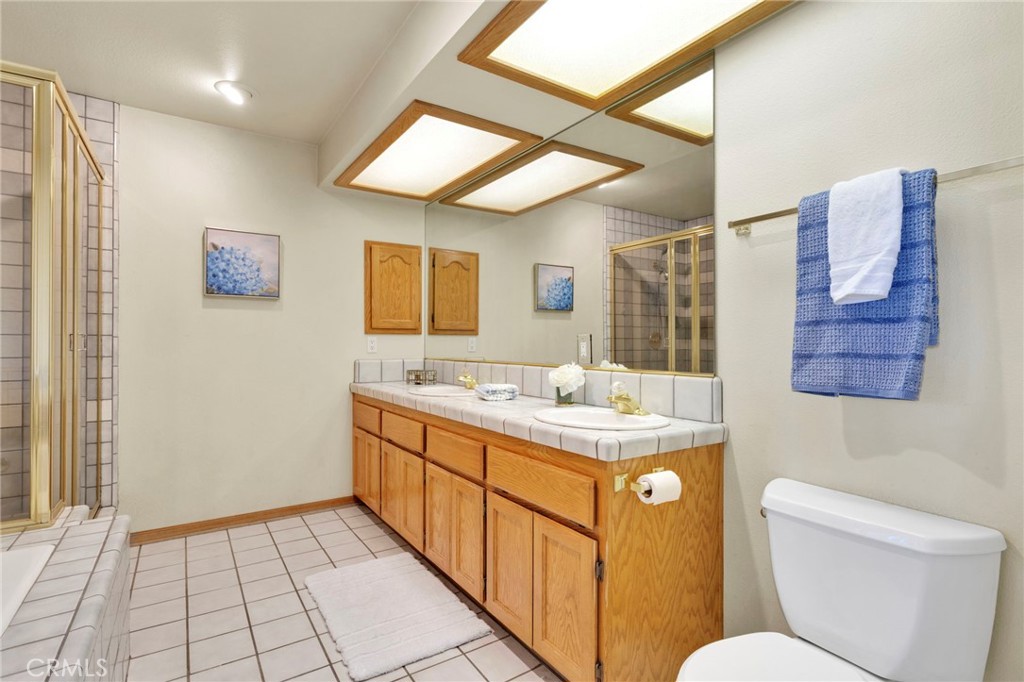 11062 Hollister Road Oak Hills, CA 92344 - Photo 31 of 69 a bathroom with a granite countertop sink a mirror and a toilet