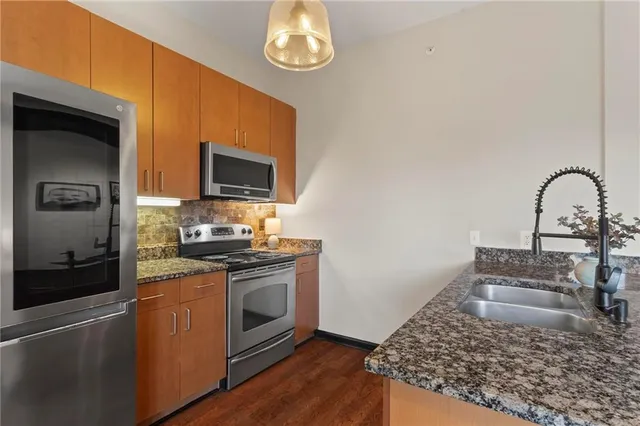 a kitchen with stainless steel appliances granite countertop a stove a sink and a microwave
