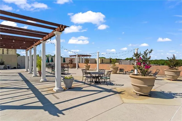 a view of a patio with dining table and chairs with potted plants and palm trees