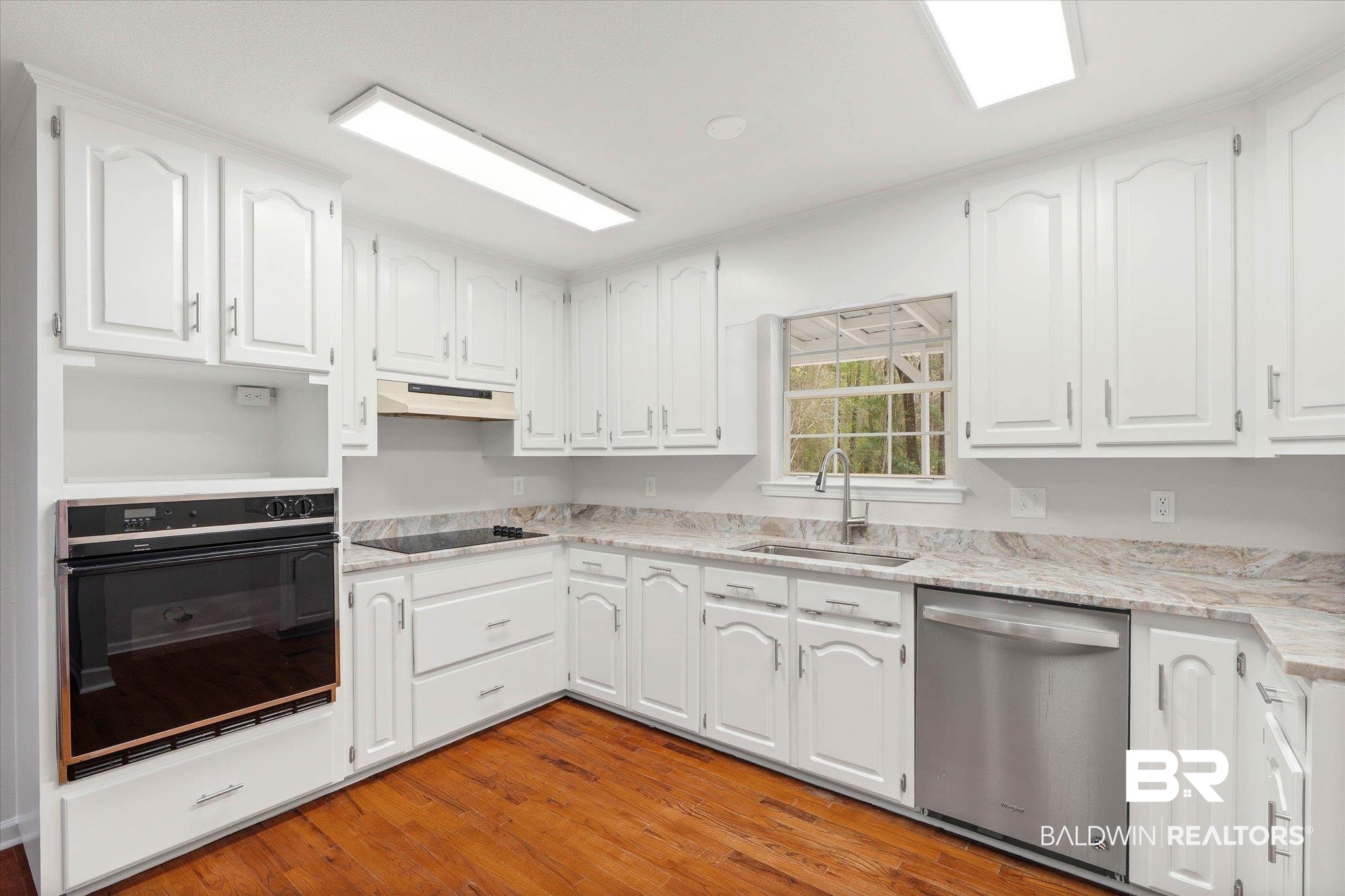 106 Melanie Loop Daphne, AL 36526 - Photo 9 of 45 Kitchen featuring black appliances, white cabinetry, light wood finished floors, and light stone countertops