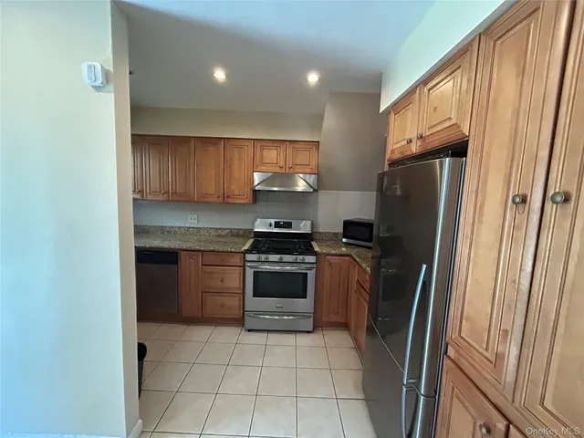 a view of a refrigerator in kitchen and an empty room