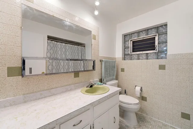 a bathroom with a granite countertop sink a mirror and a toilet