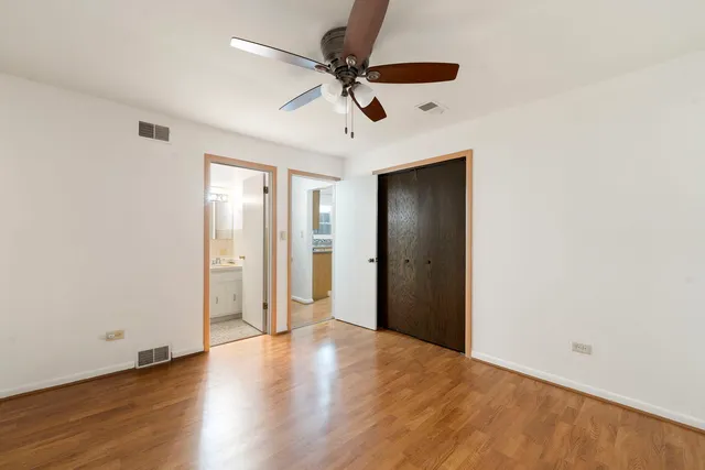 an empty room with wooden floor and ceiling fan