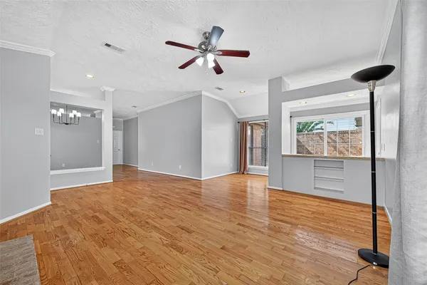 a view of an empty room with window and wooden floor