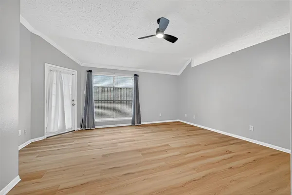 an empty room with wooden floor and windows
