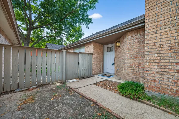 a backyard of a house with plants and trees with wooden fence