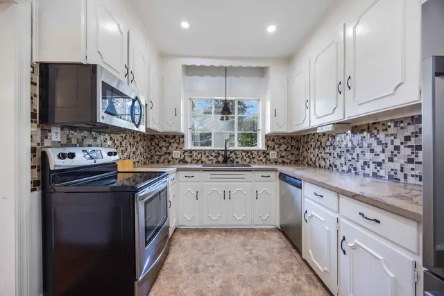 a kitchen with granite countertop a sink stove and cabinets
