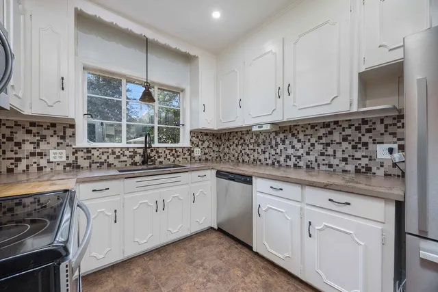 a kitchen with white cabinets and sink