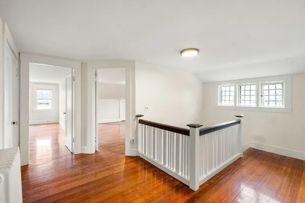a view of a hallway with wooden floor and windows
