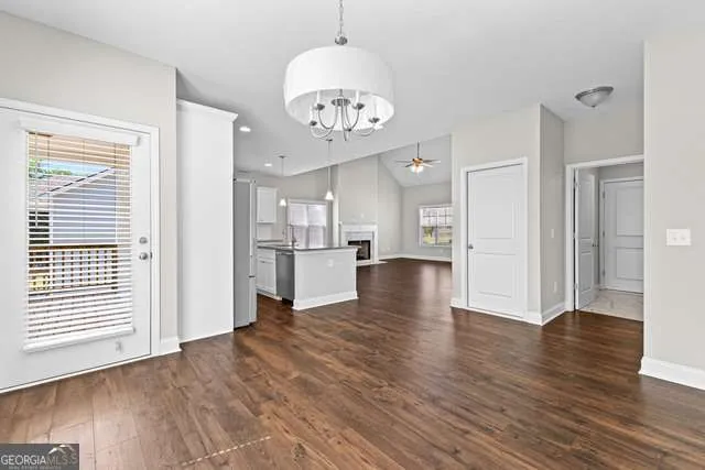 a view of an empty room and kitchen with wooden floor