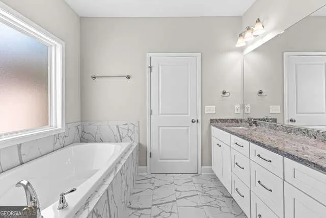 a spacious bathroom with a granite countertop sink a mirror and a