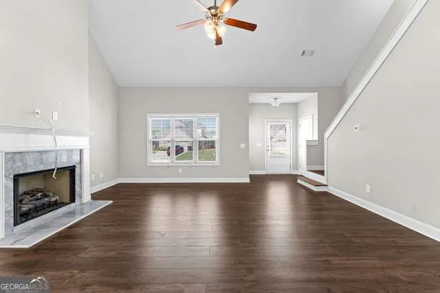 an empty room with wooden floor fireplace and windows