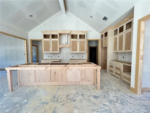 a large white kitchen with granite countertop a sink and dishwasher a stove with wooden floor