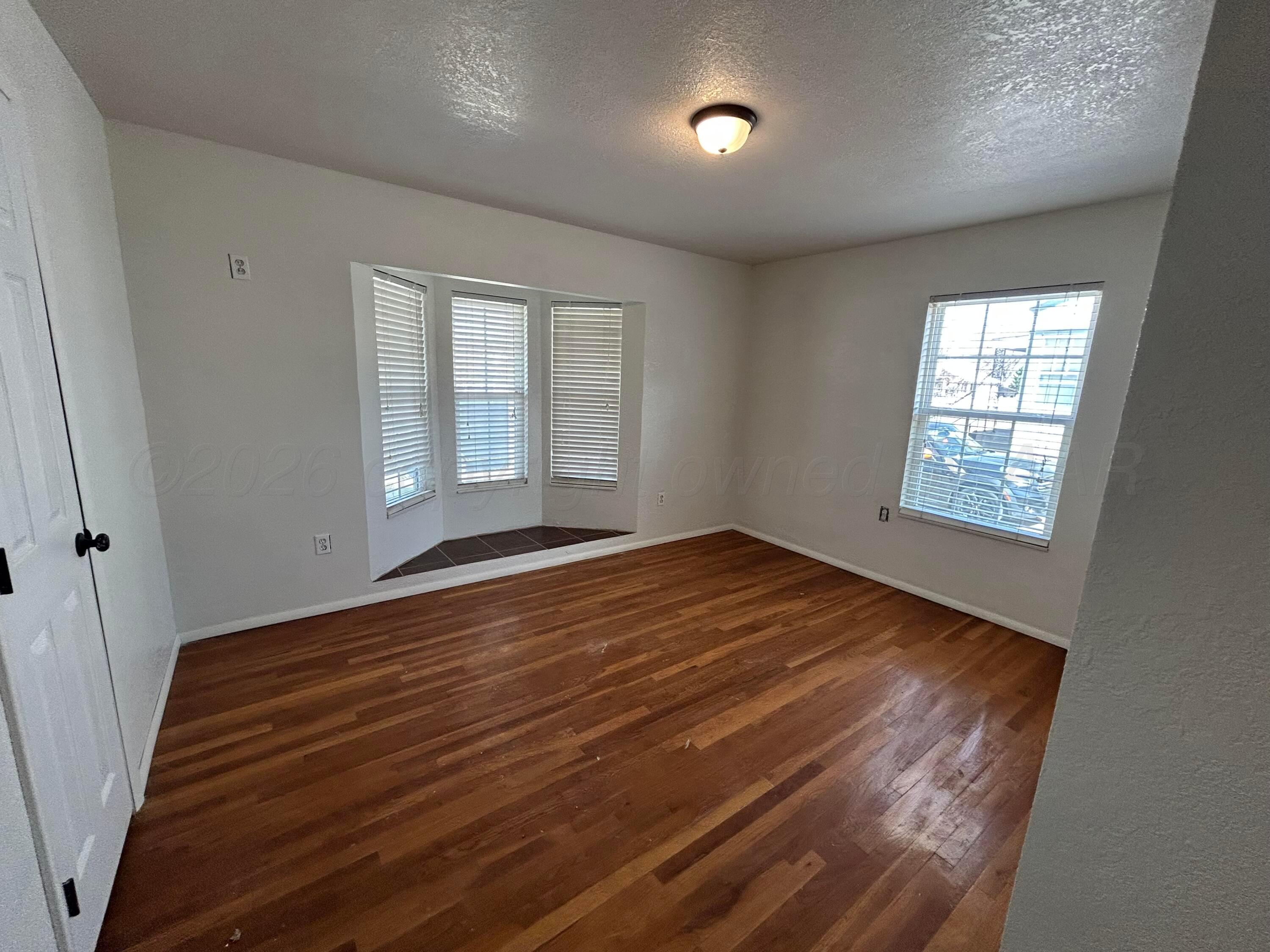923 Elmore Street Borger, TX 79007 - Photo 11 of 18 an empty room with wooden floor and windows